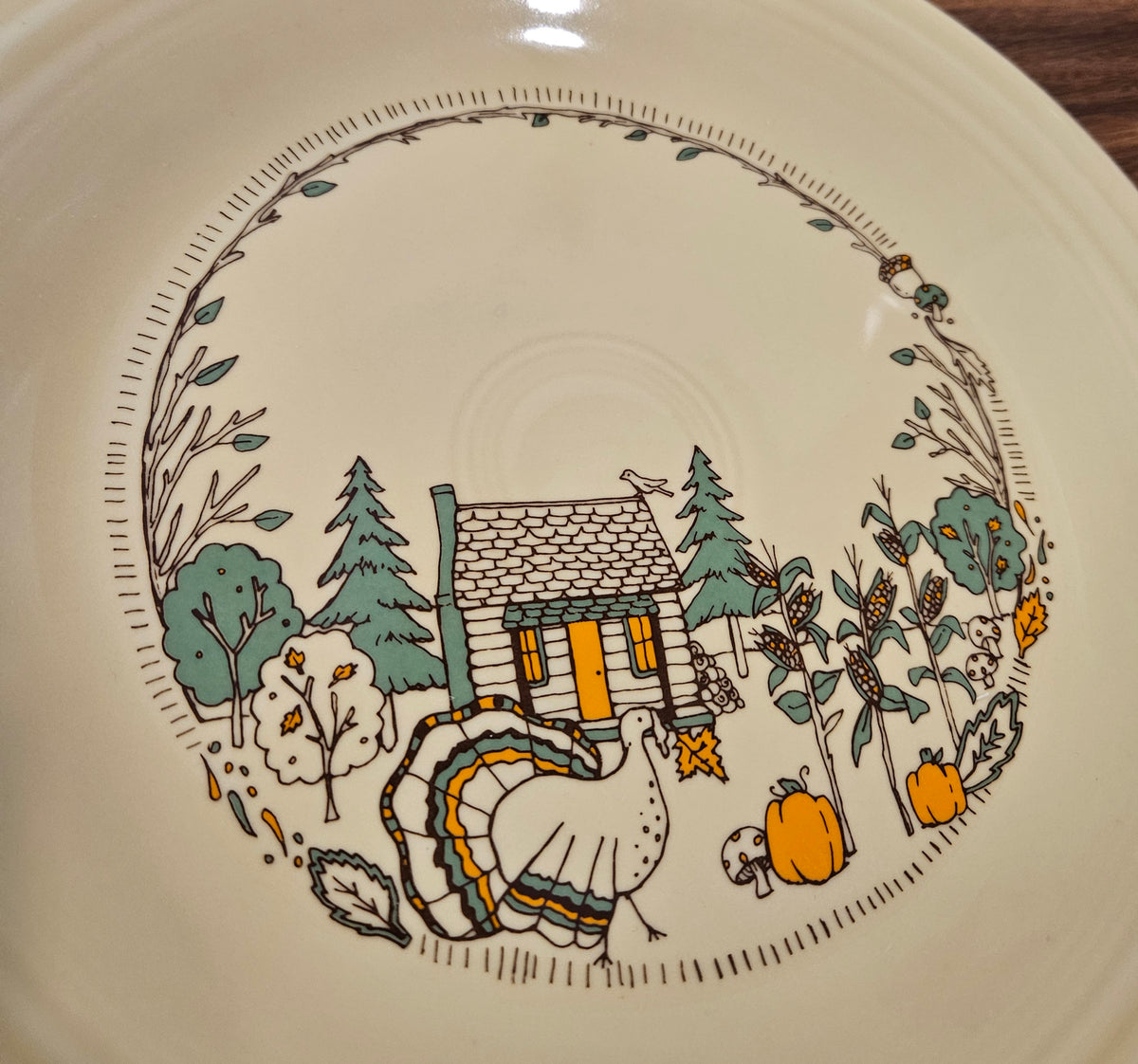 This is a Fiesta fiestaware Classic Dinner Plate featuring Everything Kitchen's Fall Forest decal on Ivory. Lead free, Post 1986 Retired Decal, Retired Color, no longer available EK, Fall, Pumpkin, Greenery, Cabin, Bird, Turkey, Thanksgiving
