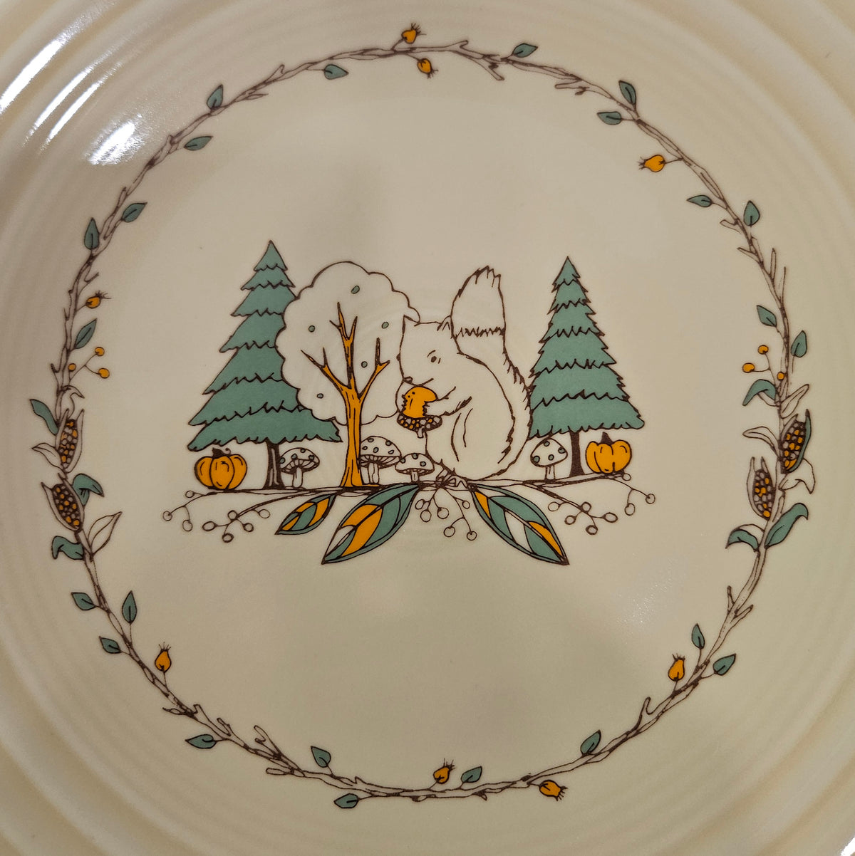 This is a Fiesta fiestaware Classic Luncheon Plate featuring Everything Kitchen's Fall Forest decal on Ivory. Lead free, Post 1986 Retired Decal, Retired Color, limited quantities available via EK, Fall, Pumpkin, Greenery, Bird. Acorn, squirrel, Thanksgiving
