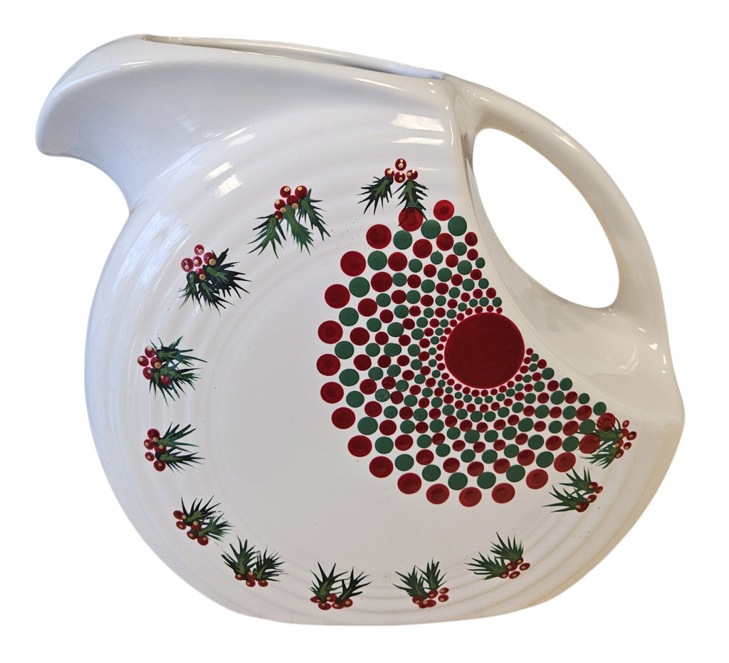 This is a Fiesta Fiestaware Large Disk Pitcher featuring hand-painted artwork by Patricia Degraw on white. The artwork is reflective of Christmas and the Holidays with reds and greens paint hues, holly and berries and a partial mandala pattern. Decorated, Post-1986, Lead-Free
