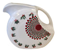 This is a Fiesta Fiestaware Large Disk Pitcher featuring hand-painted artwork by Patricia Degraw on white. The artwork is reflective of Christmas and the Holidays with reds and greens paint hues, holly and berries and a partial mandala pattern. Decorated, Post-1986, Lead-Free
