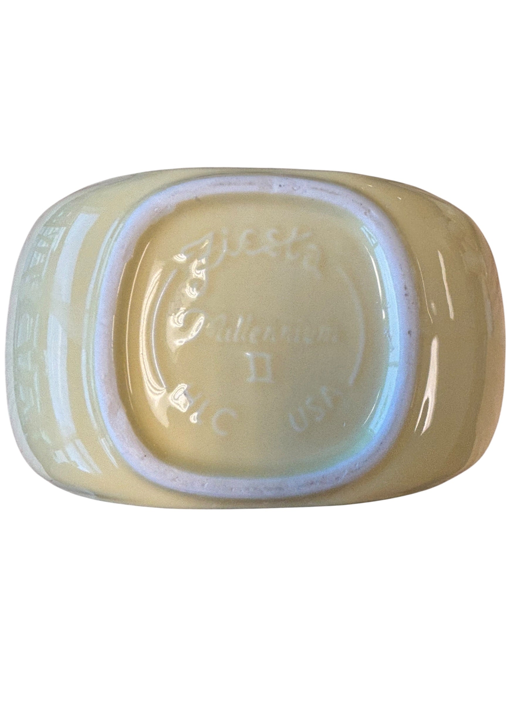 A vintage oval ceramic ashtray with a pearlescent iridescent finish, showing the underside with embossed text and a light blue iridescent rim against a white background. Fiesta Millennium II Vase Yellow